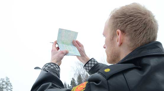 Bilde av politimann som undersøker et pass. Foto.